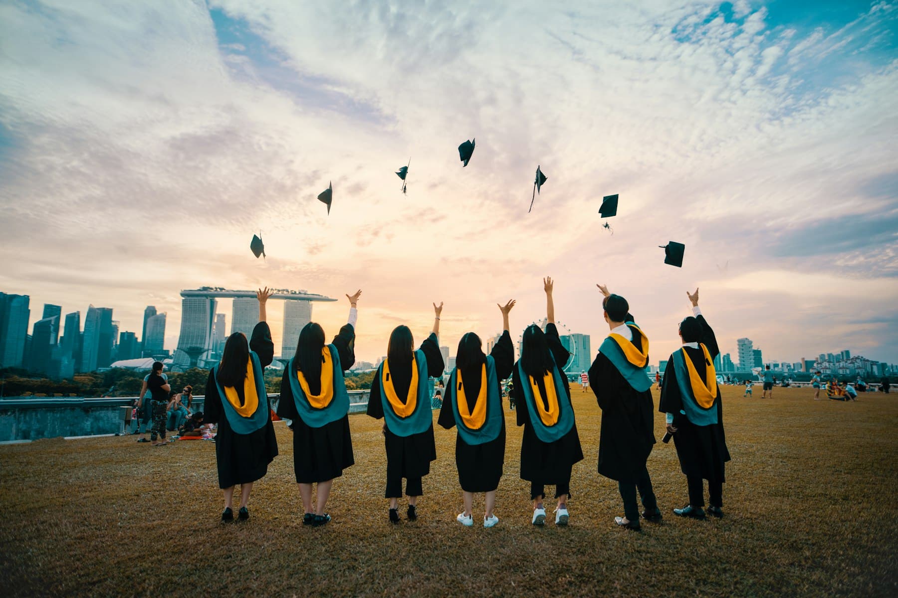 Graduates throwing their caps in front of a city skyline